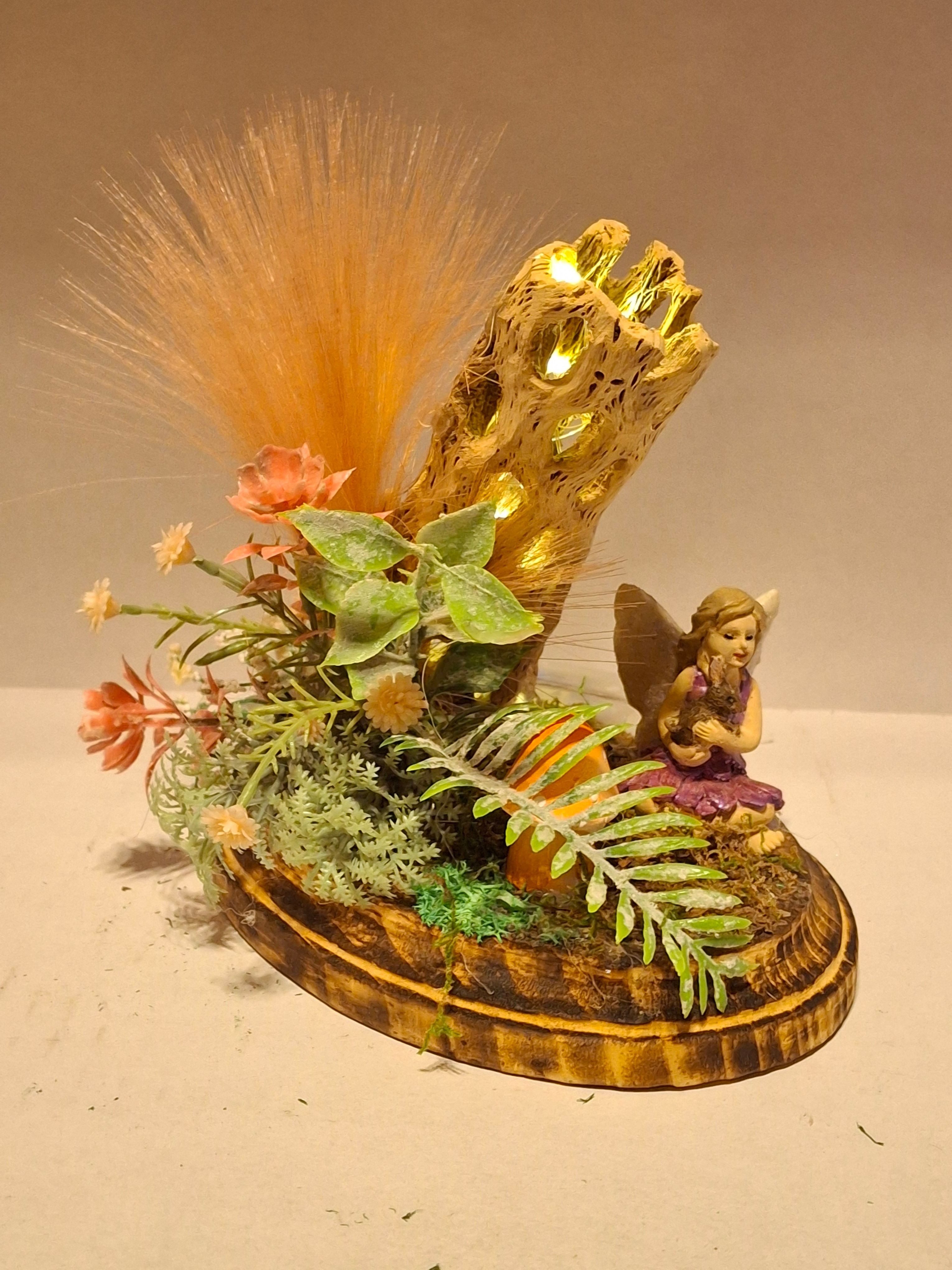 Decorative arrangement with a gold-colored object, plants, and feathers on a round base, viewed from the side.