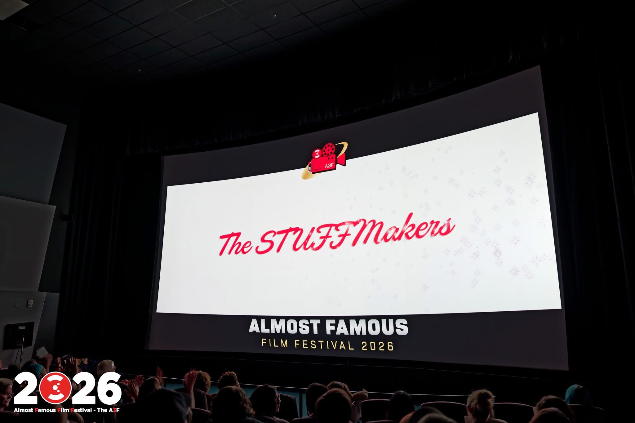 Large movie theater screen displaying the text 'The STUFFI Makers' and 'ALMOST FAMOUS' at a film festival, with audience silhouettes in foreground.