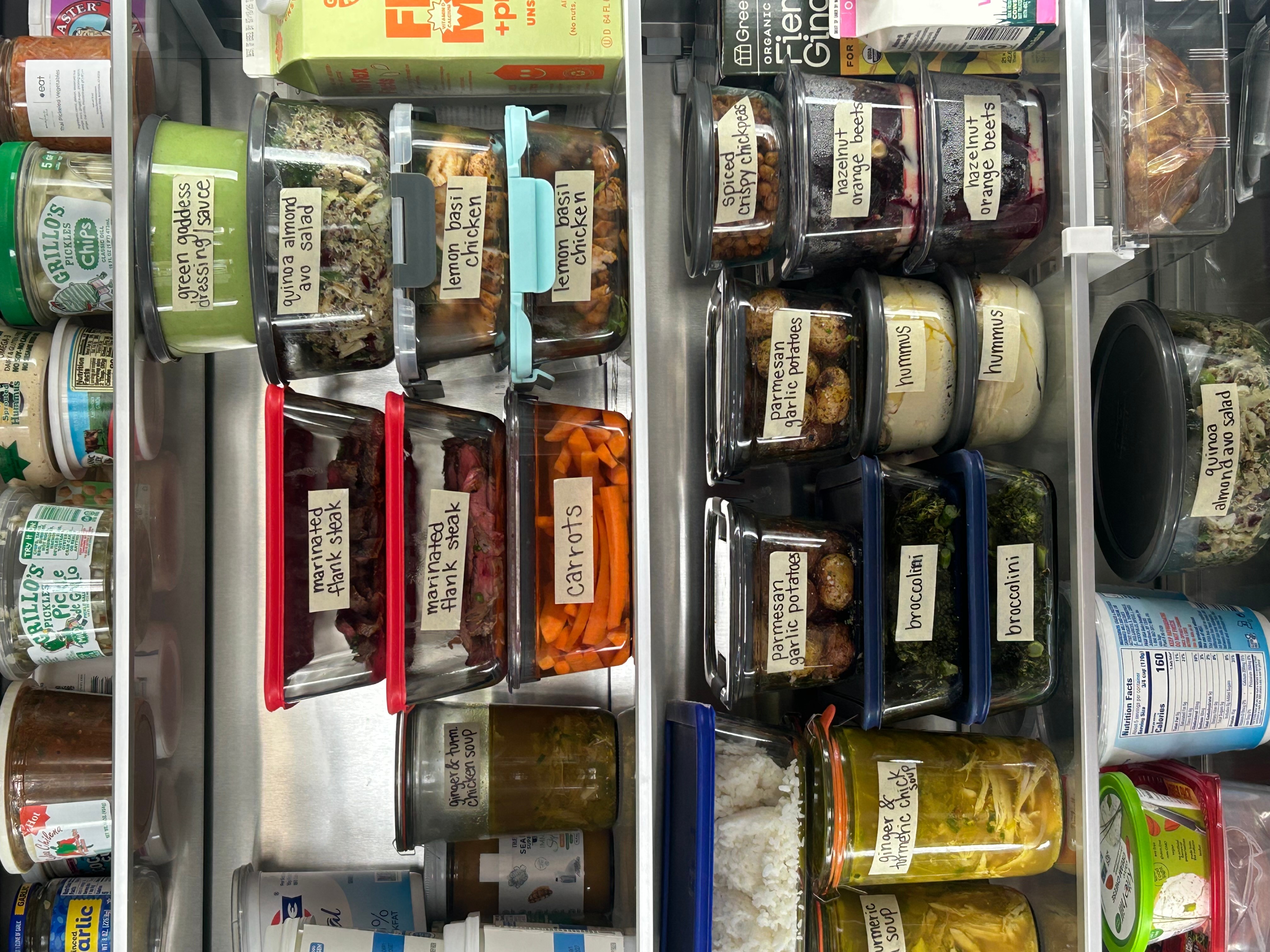 Shelf with jars and containers of spices and herbs, labeled with handwritten tags, organized in rows.