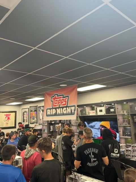 People gather at a food court with a sign reading 'Topps DIN NIGHT' in the background.