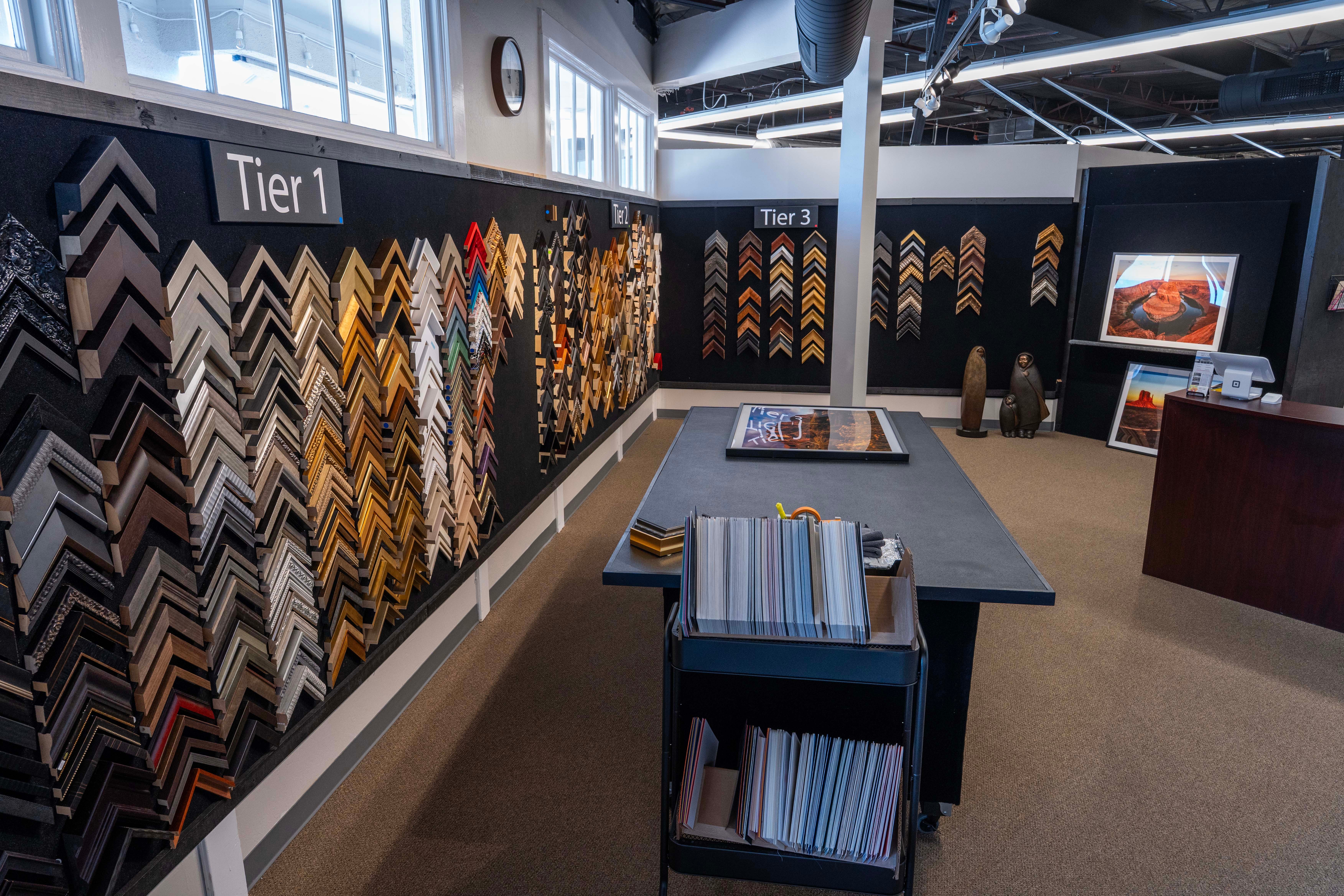Display of various tile samples on walls, with a table and chairs in a showroom setting.
