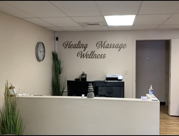 Reception area with a wall clock, potted plants, and a sign reading 'Healing Massage Wellness'.